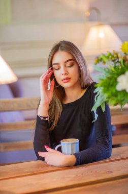 Bir kızın portresi. Kahve dükkanında esmer. Siyah elbiseli zarif bir bayan, bir restoranda tek başına. Kafedeki kız.