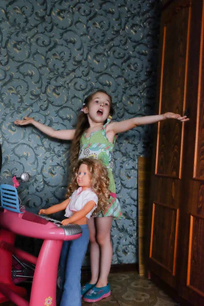 女の子が部屋で遊んでいる 家にいる少女 ブロンドの髪をした愛らしい幼児の女の子は人形と屋内で遊んでいます 家にいて — ストック写真
