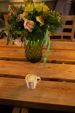 Tahta masada bir fincan sıcak cappuccino kahve. Kahve fincanının içinde kahve ile kapuçino bir kafede masanın üstünde. Seçici odaklanma. - Evde. Rahatlama zamanı. Masanın üzerinde pembe kahve bardağı.