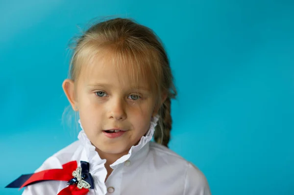青いスタジオの背景に隔離された白いTシャツの愛らしい6歳の少女は ヨーロッパの外観の子は カメラで室内の笑みを浮かべて見てポーズ 世代Zの概念 青を背景にした女子高生 — ストック写真