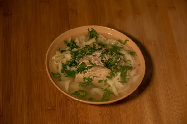 Chicken Noodle Soup. Chicken and noodle soup on an orange tablecloth in an orange plate. Food photography. Hot dish. Broth with noodles. Chicken, noodles. Homemade noodles and broth. Dill and parsley