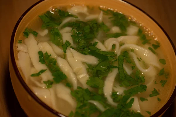 Chicken Noodle Soup. Chicken and noodle soup on an orange tablecloth in an orange plate. Food photography. Hot dish. Broth with noodles. Chicken, noodles. Homemade noodles and broth. Dill and parsley