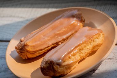 Kremalı kremalı kremalı kek. Üzerine kahverengi ve beyaz şekerli krema dökülmüş muhallebi kekleri. Çay ya da kahve için tatlı ikramları. Yakın plan. Seçici odaklanma. Kremalı pasta. Tatlı. Bej bir tabakta dört kek