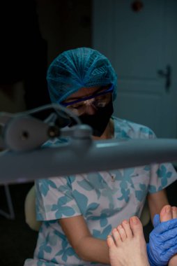 Güzellik salonunda profesyonel pedikür. Güzellik uzmanı deriyi tırnaklarıyla keser ve profesyonel pedikür yapar. Podoloji tedavisi. Ayak hastalıkları uzmanı. Sağlık, vücut bakımı kavramı.