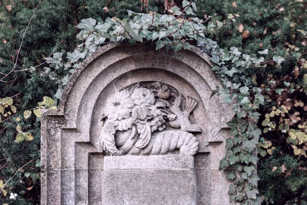 Una tomba di cimitero di pietra con fiori in rilievo — Foto Stock