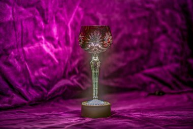 Close up of an illuminated red bohemian crystal wine glass with velvet background clipart