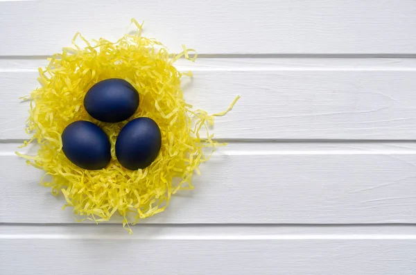 Зі святом Великодня - місце для тексту. Сині великодні яйця в жовтому гнізді на білому дерев'яному фоні, вибіркове зображення фокусу. яскравий контраст порожній для святкової листівки — стокове фото