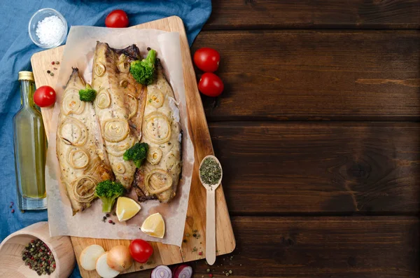 Oven baked mackerel with chopped onion rings, broccoli, tomatoes and lemon on a dark wooden background with a blue napkin. keto and flexitarian diet and healthy eating. — Stock fotografie