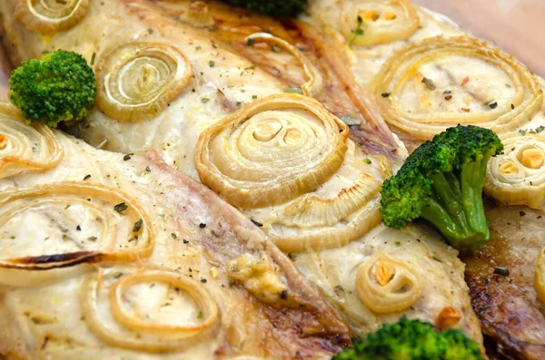 Detailní čerstvé měkké pečené makrely s kroužky nakrájené cibule, brokolice a citronu na tmavé dřevěné řezací desce v pečicím papíru. keto a flexitářská strava a zdravé stravování. — Stock fotografie