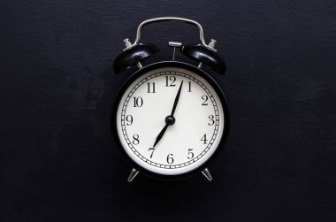 Beyaz kadranlı bir siyah alarm saati, metin için yeri olan siyah bir arkaplanda 7 saatlik zamanı gösterir