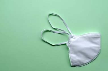Grip ve diğer hastalıklara karşı korunmak için beyaz tıbbi maske. Cerrahi yüz kalkanı. Hafif yeşil bir arka planda tıbbi solunum bandajı suratı. Virüs ve salgın önleme