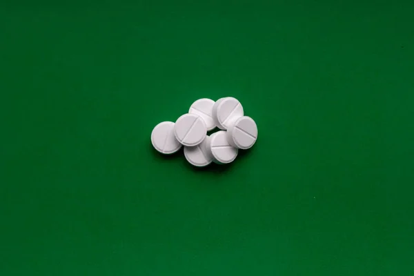 Λευκό συνθλίβονται χάπια σε πράσινο φόντο. Συντετριμμένα δισκία. Ιστορικό ιατρικής. — Φωτογραφία Αρχείου