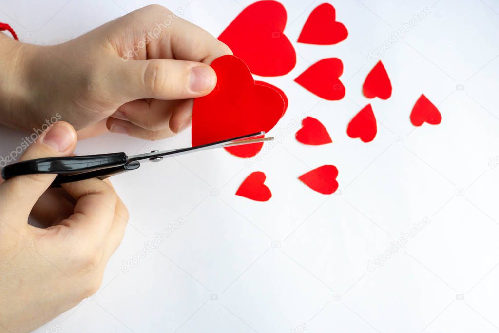 large iron scissors cuts the paper heart paper hearts on a white background