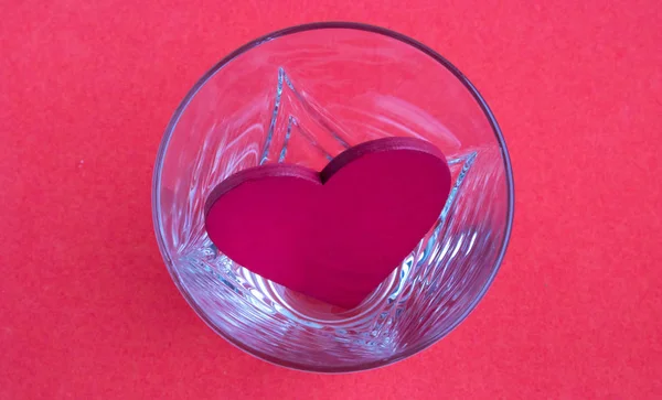 The top view of glass cup heart shape with red tea, and blurred hearts at the background, on pink background, romantic and Valentine 's concept — стоковое фото