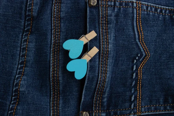 Small clothespins with blue hearts on the pocket of blue jeans.