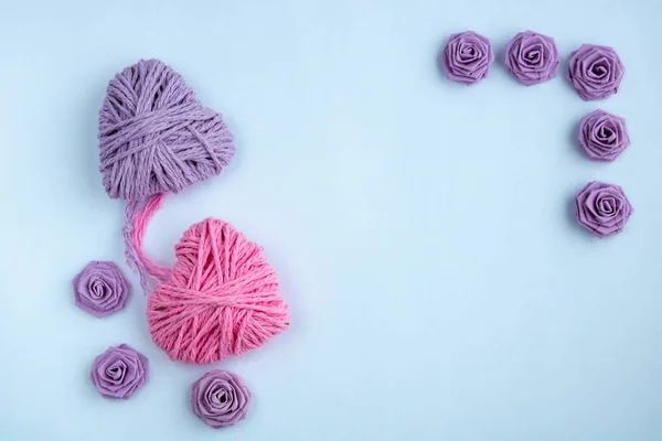 Dos corazones rosas y lila hechos de hilos sobre un fondo blanco tejido en un nudo — Foto de Stock