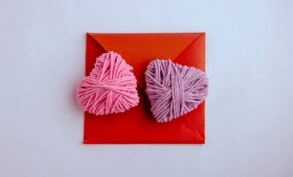 Hilado de punto rosa y lila en forma de corazón. San Valentín concepto mínimo día. Tarjeta de felicitación con corazón sobre fondo rosa. Vista superior. Puesta plana . — Foto de Stock