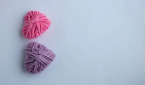 Hilado de punto rosa y lila en forma de corazón. San Valentín concepto mínimo día. Tarjeta de felicitación con corazón sobre fondo rosa. Vista superior. Copiar espacio . — Foto de Stock