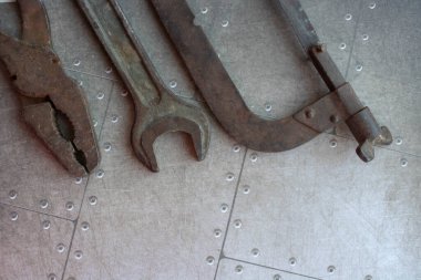 Paslı anahtar ve testere eski bir çatlak yüzeyde. Atölyedeki eski aletler