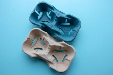 Kahverengi mukavvanın ön ve arka tarafı bir bardak veya bardak koymak için, içecekler veya sıvılar içeren kapların düşmesini önler, mavi arka planda kırpma yolu ile izole edilir..