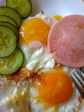 Sahanda yumurta, sebze salatası ve arka planda kızarmış peynirli sandviç.