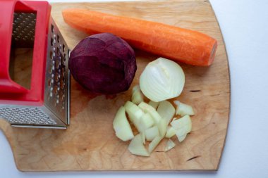 Borç için taze sebzeler rendenin yanındaki kesme tahtasının üzerinde..