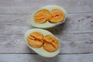 Haşlanmış yumurtanın iki yarısı ahşap bir arka planda izole edilmiş.