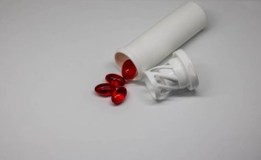 Sıcaklık ve basınçtan dolayı kırmızı kapsüller. Kapsüller ve şişe beyaz arka planda. Metin için boşluk.