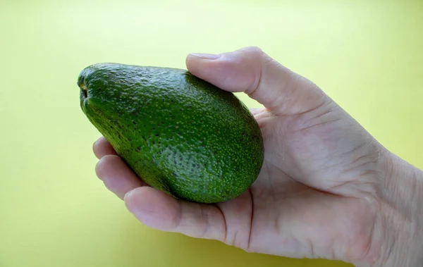 Половина Авокадо Костью Руке Желтом Фоне — стоковое фото