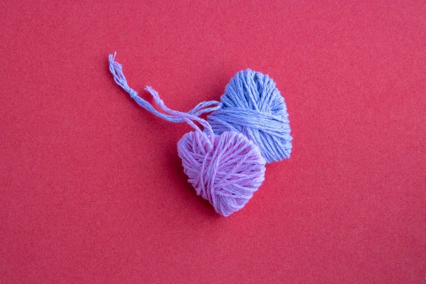 Mother's day, pink and lilac knitting yarn in the shape of a heart. Valentine's day, March 8, minimal concept. Greeting card with a heart on a pink background. The view from the top.