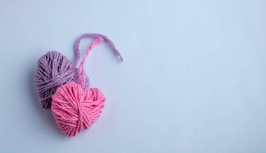 Pembe ve leylak örgü, kalp şeklinde. Sevgililer Günü minimum konsept. Pembe arka planda kalbi olan bir tebrik kartı. Üst Manzara. Boşluğu kopyala.