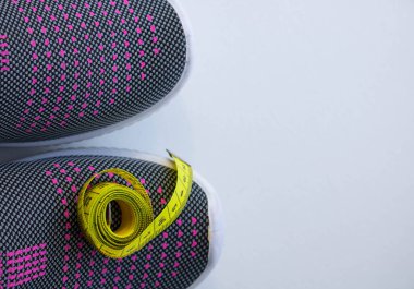 Beyaz arka planda bir santimetre boyunda leylak rengi spor ayakkabılar. Mesaj için yer var..