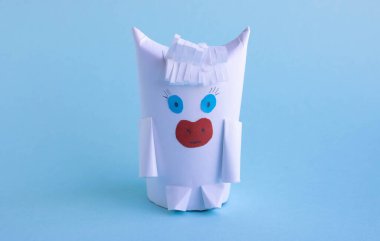 Mavi arka planda kağıt ve tuvalet kağıdından yapılmış komik beyaz boğa. Yeni yıl fantezisi.