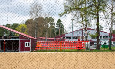 Birkaç sıra seyirci koltuğu ve spor stadyumunda tenis kortu olan bir spor stadyumu.