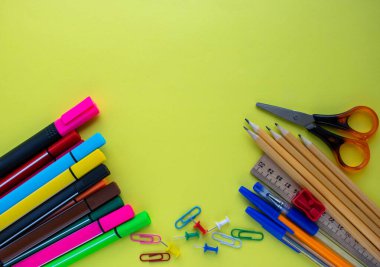 Bir sürü ofis malzemesi ve sarı arka planda beyaz kulaklıklar. Yakın çekim, kopyalama alanı, düz uzanma, üst görünüm.