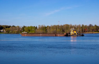 Bahar nehrinde ağır bir mavnayı iten bir römorkör.