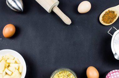 Pişirme ve pişirme konsepti. Siyah katı arka planda pişirme malzemeleri. Yumurtalar, uzay merkezinin fotokopisi, un ve masa örtüsü. Ev yapımı pişirme, ev yapımı yemek düz bir görünüm.