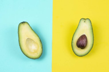 Renkli arka planda iki dilim doğal organik yeşil avokado som sarı ve katı cyan arkaplan.