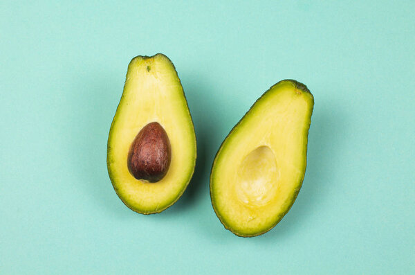 Top view flat lay of photo with two natural bio organic slices avocado on the solid cyan background