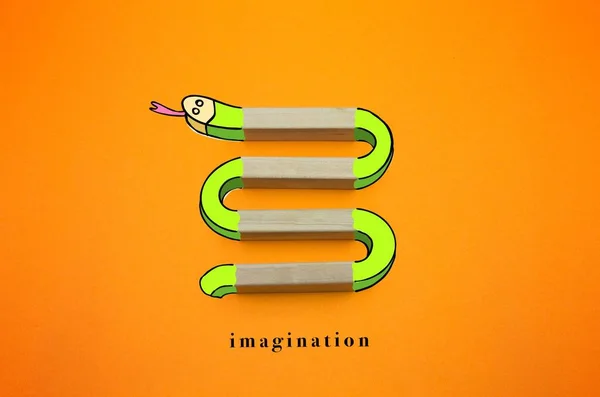 imagination - drawing snake made of wooden blocks. copy space and orange gradient background