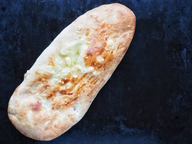 Koyu siyah arkaplanda fotokopi alanı olan bir somun ekmek.