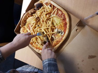 Pizza siparişi, pizza kutusundaki pizzayı dilimleyen biri.