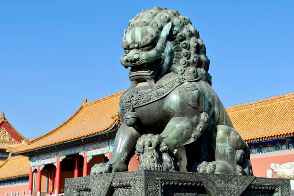 bronze lions on the background of the buildings of the imperial palace. The Imperial Palace in Beijing