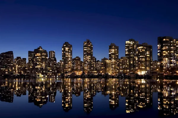 Vancouver skyscrapers at night. Buildings are reflected in the water. Falls Creek Embankment