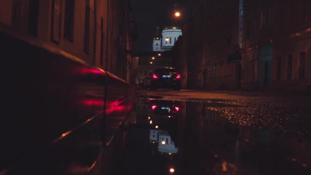 MOSCÚ, RUSIA - 26 DE OCTUBRE DE 2019: Un coche reflejado en un charco, sale a lo largo de un callejón, al fondo de la Catedral de Moscú de Cristo Salvador — Vídeo de stock