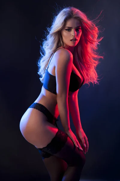 Sexy schöne Blondine in schwarzen Dessous isoliert auf dunklem Hintergrund. — Stockfoto
