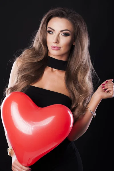 Sexy Frau im schwarzen Kleid mit rotem Herzballon. — Stockfoto