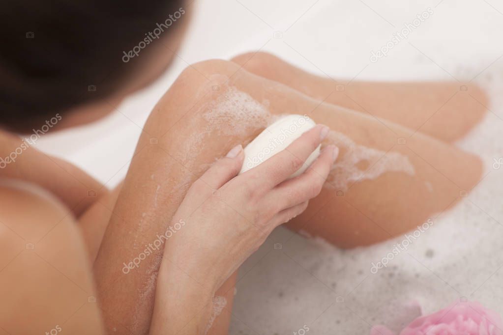 Bath time. Woman is taking bath with soap.