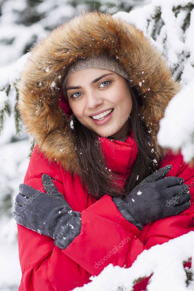 Beautiful woman is happy while is snowing in the park.