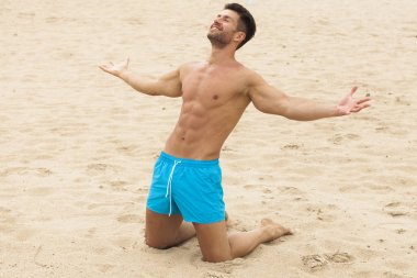 Genç, yakışıklı bir adam sahilde eğleniyor.